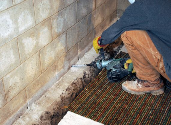 A man drilling into concrete walls